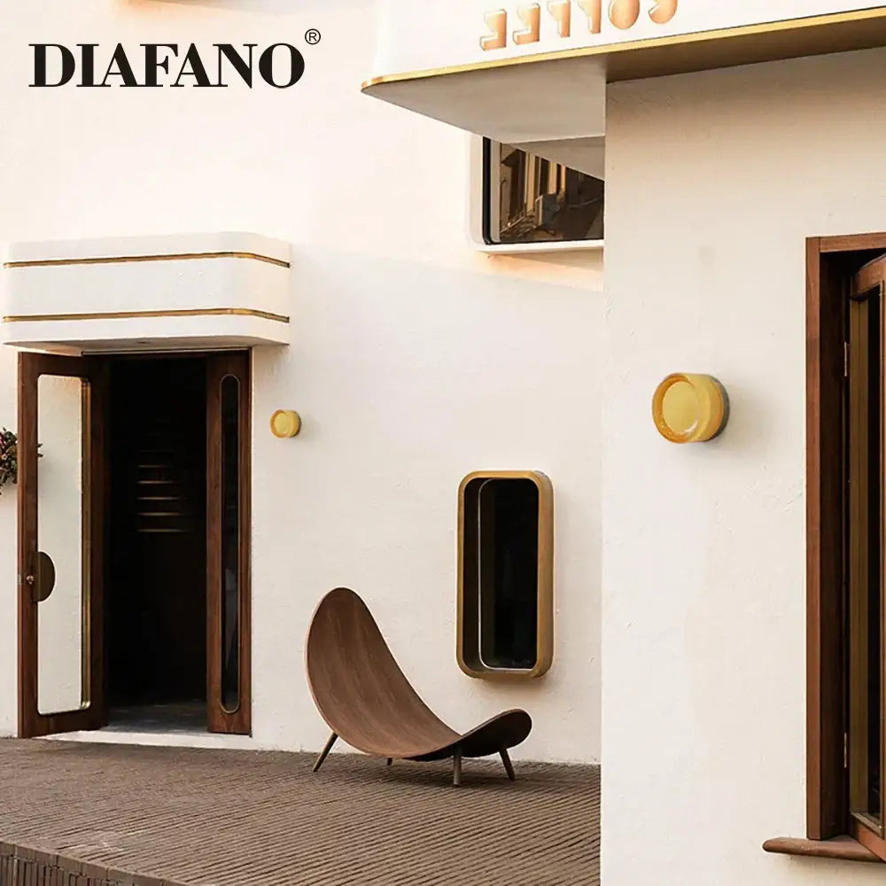 Modern wooden lounge chair with curved design and dark brown finish next to a modern amber and white glass sconce led wall lamp