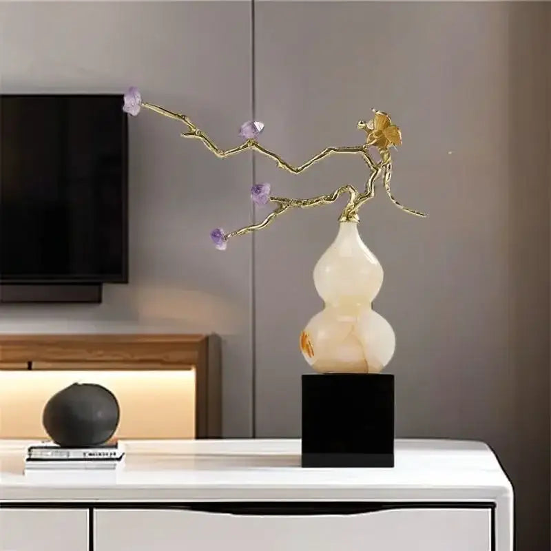 A gold-toned branch sculpture with purple amethyst blossoms rises from a creamy white crystal jade gourd wealth decorbites ornament