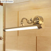 Modern antique brass integrated led wall light with brass finish ribbed cylindrical lamp and ornate scrollwork arm for vanity