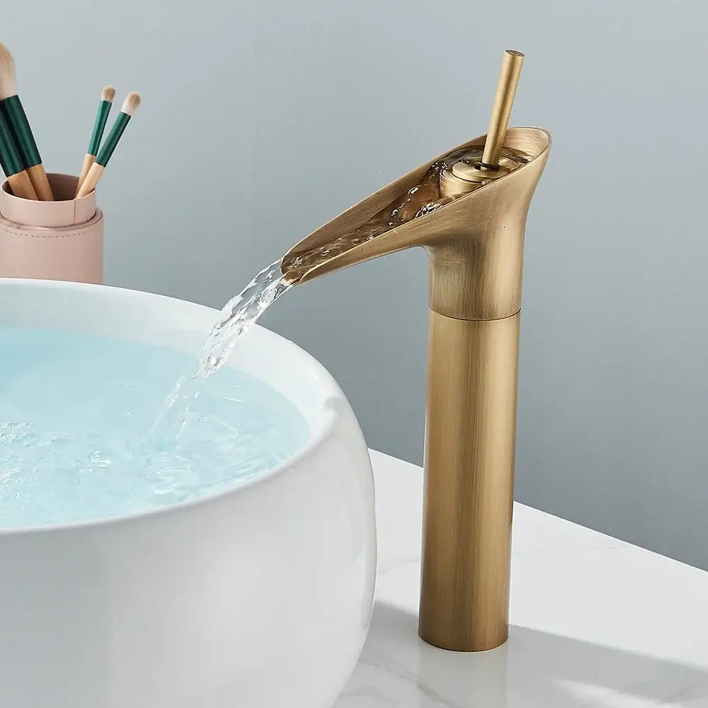 Modern antique brass finish waterfall faucet with matte black accents and sleek cylindrical spout for bathroom sink tap
