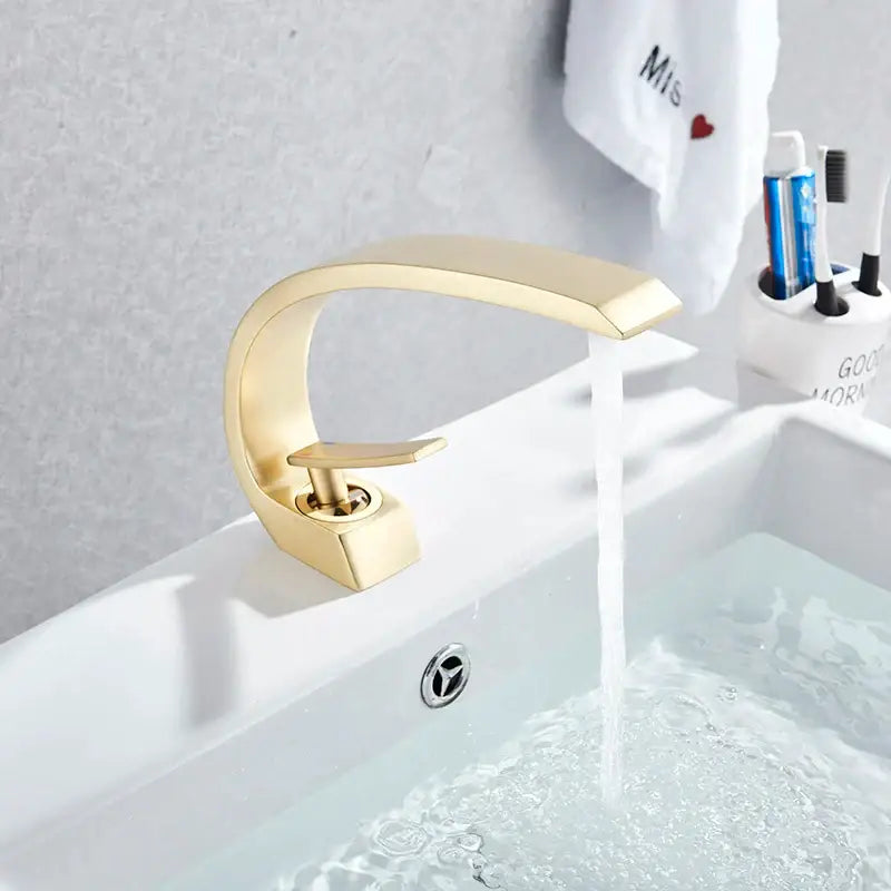 Modern arched brushed gold basin faucet with a sleek curved design and polished metallic finish for bathroom use