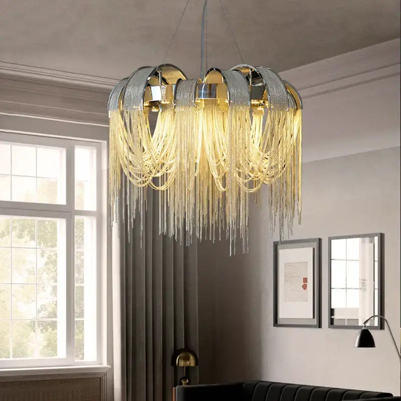 Modern arched gold aluminum chain chandelier with a metallic leaf frame and cascading golden chains emitting warm light