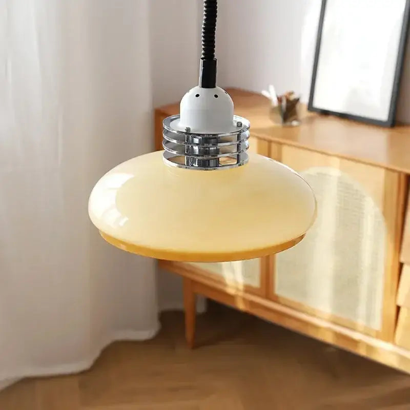 A sleek pale yellow glass led chandelier pendant light with chrome metal collar and black cord for dining room use