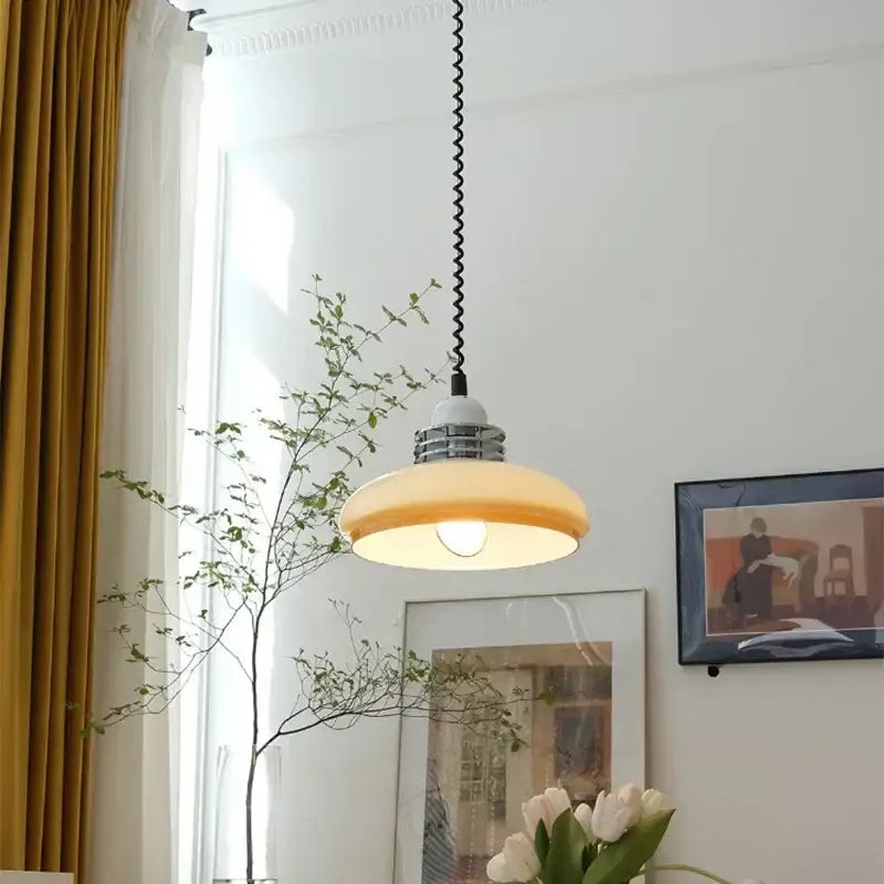 A warm amber glass led chandelier pendant lamp with vintage industrial design and black coiled suspension cord