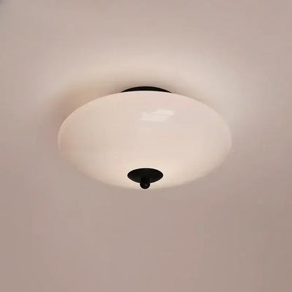 A sleek modern bauhaus cream white glass ceiling lamp with black metal hardware for bedroom lighting