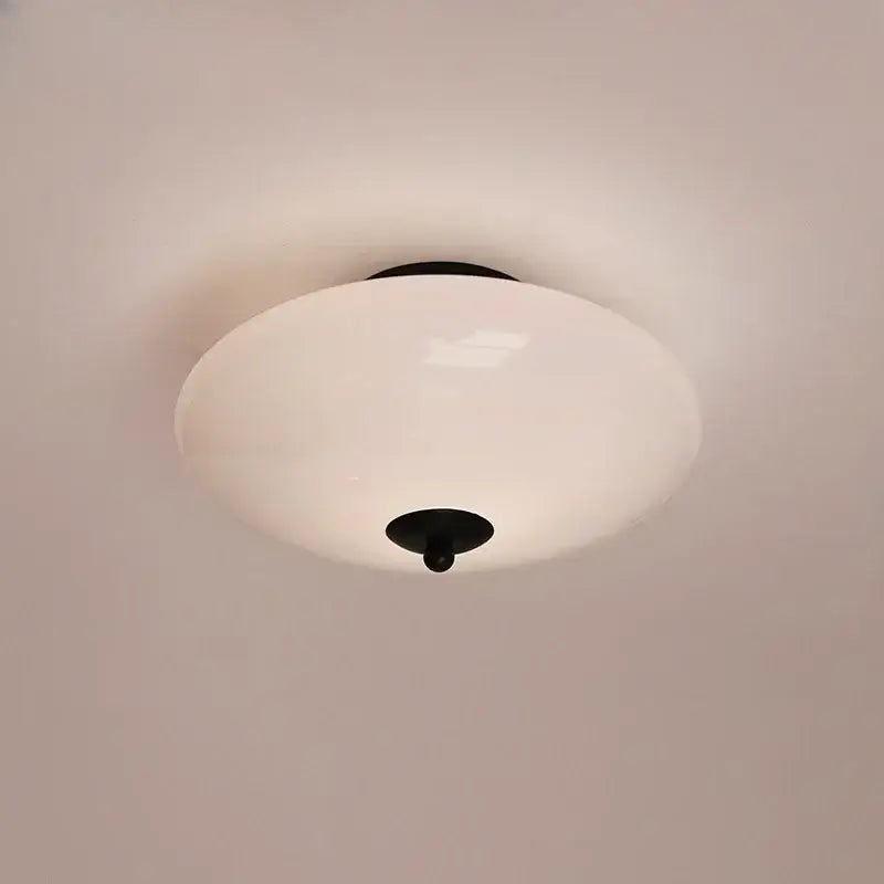 A sleek modern bauhaus cream white glass ceiling lamp with black metal hardware for bedroom lighting