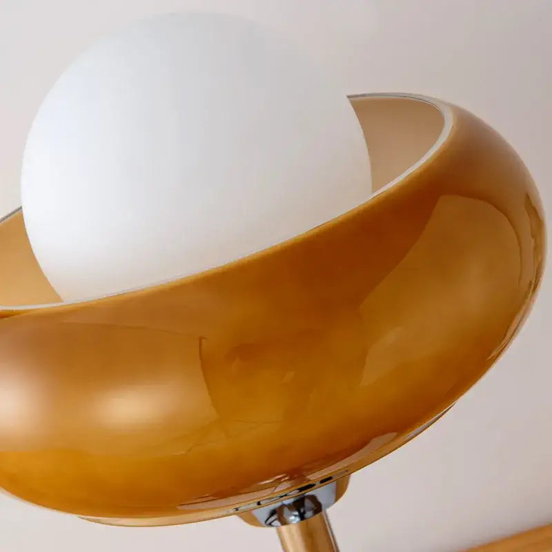 A modern bauhaus table lamp with amber glass bowl shade and white spherical bulb by guzzini modern decorbites