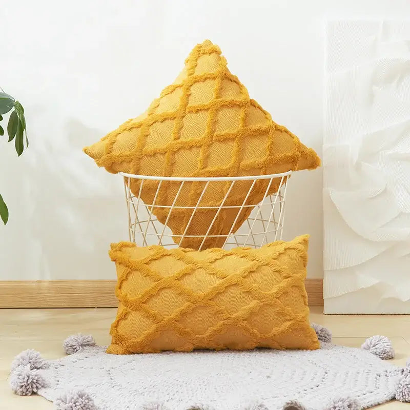 A mustard yellow solid embroidery cushion cover with diamond solid embroidery and frayed edges in a wire basket