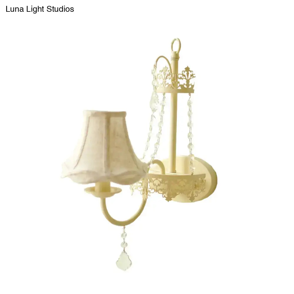 Cream-colored wrought iron modern beige ornate crystal wall sconce with floral cutouts and fabric shade 15 inch fixture
