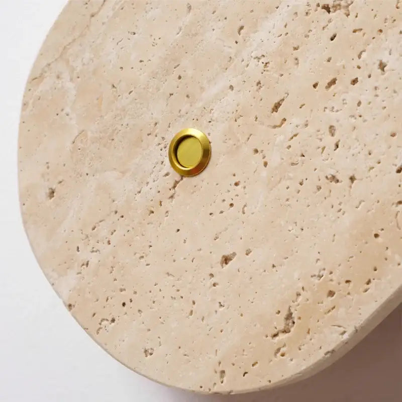 A sleek circular brass doorbell button set into beige stone surface complements modern beige stone led wall light decorbites led wall