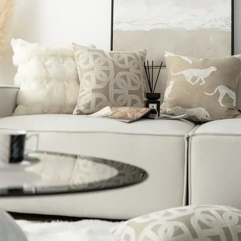 Beige and white jacquard cushion covers with geometric and leaping cat embroidery on a modern white sofa decorbites design