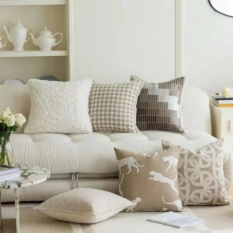 Modern beige and white jacquard cushion covers with embroidered leaping cat and geometric patterns on cream sofa decorbites