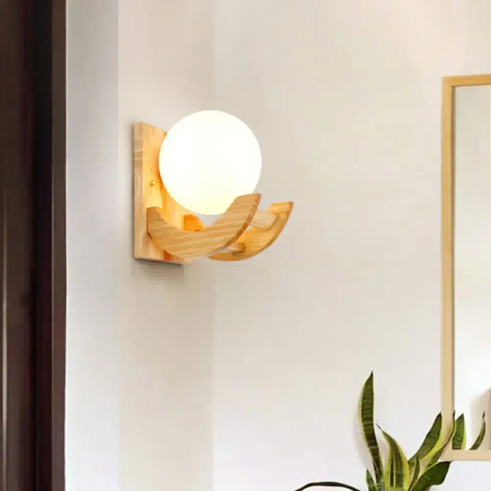 Modern beige wood sconce light fixture with frosted white globe and curved wood arms wall lamp for bedroom use