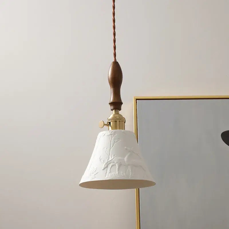 Modern bell ceramic led pendant light in white with embossed deer and tree design, suspended by twisted brown cord and brass hardware