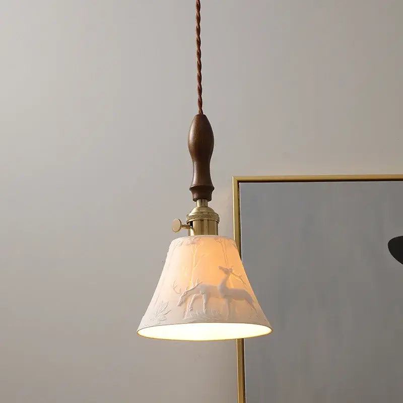 A warm cream ceramic led pendant light with deer embossed design and dark wood stem for modern bedroom decor