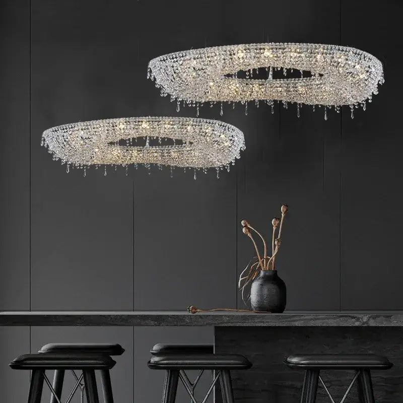 Two elegant circular bird nest crystal pendant chandeliers with cascading droplets hang in a modern living room