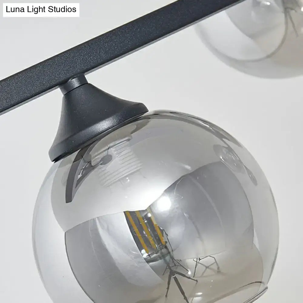 A sleek black metal decorbites dome glass ceiling light with smoke gray globe housing led bulb for dining table lighting