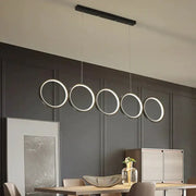 Modern black metal pendant light features five illuminated circular LED rings in a row for hanging island light use