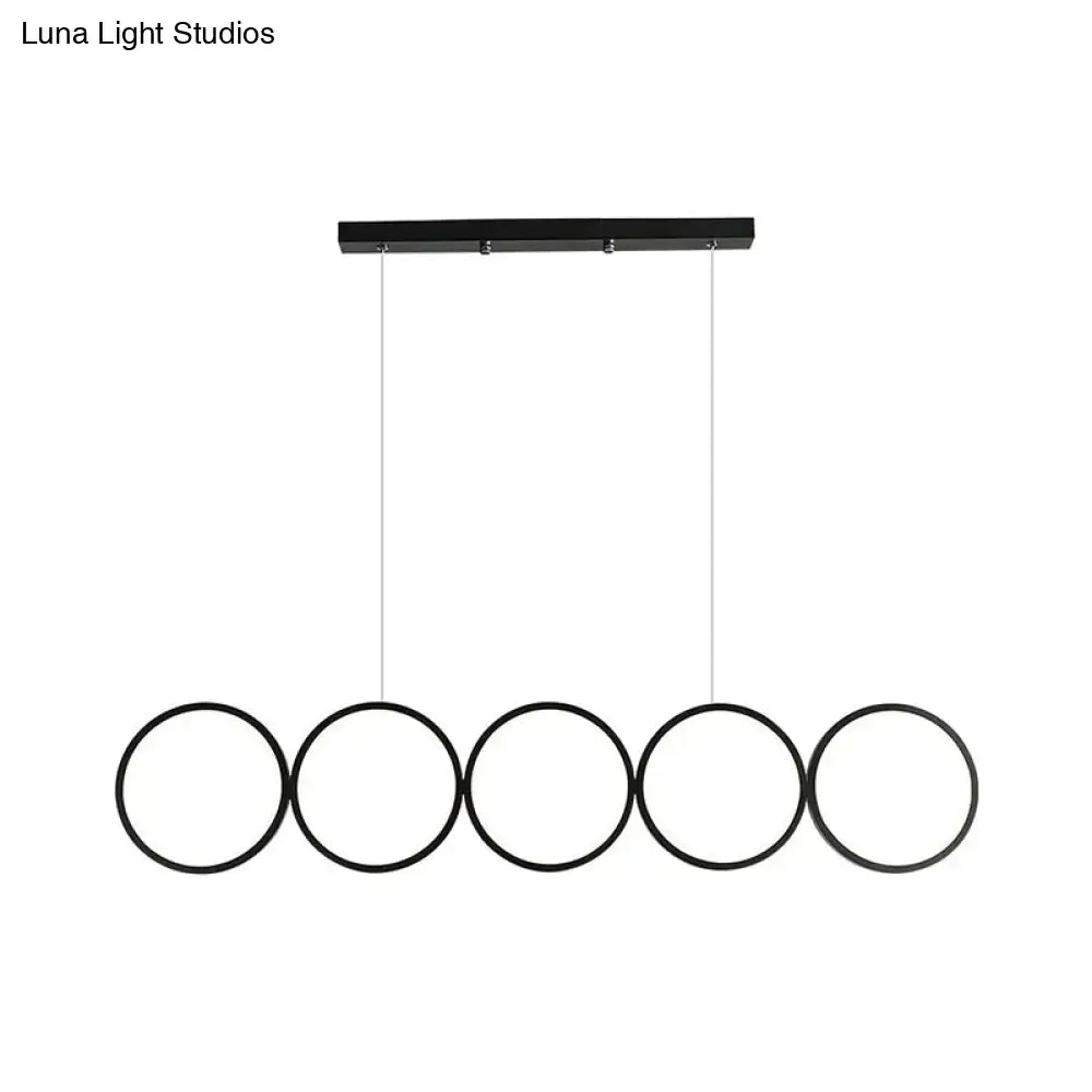 Black metal DecorBites pendant light with five circular rings hanging from a rectangular bar for island lighting