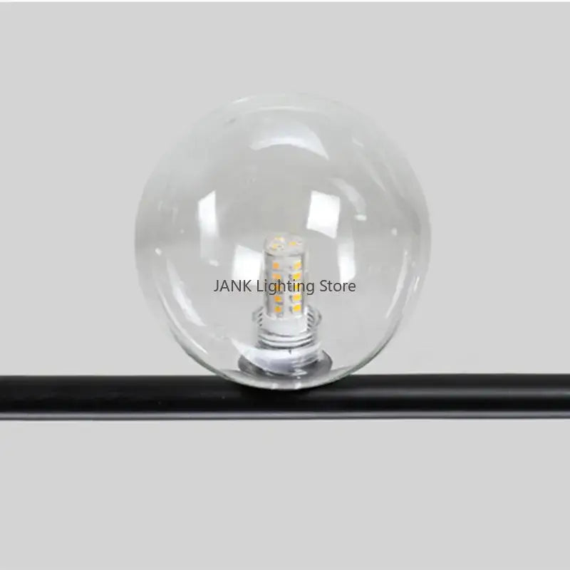 Modern black 7 light glass shade pendant light featuring a clear glass globe with multiple yellowish leds mounted on a black rod