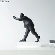 Modern black abstract resin sculpture of a stylized overweight figure in mid-stride on a white base for home decor