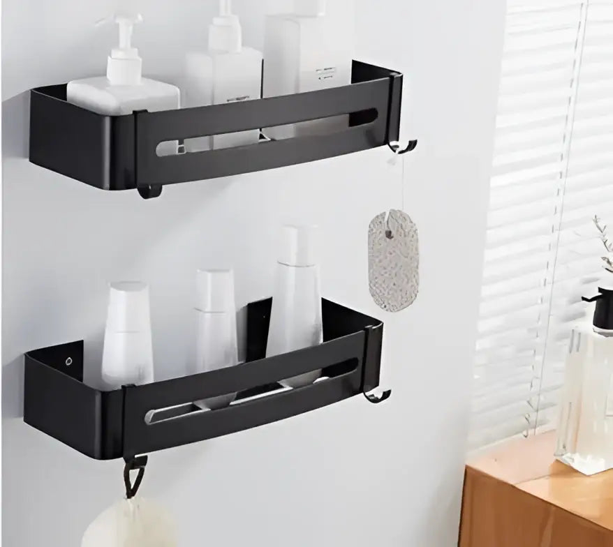 Black aluminum wall-mounted corner shelf with two tiers holding white bottles and hooks for hanging accessories