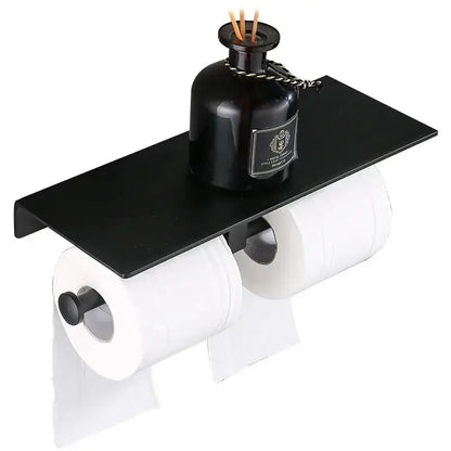 Modern black aluminum toilet paper holder with shelf featuring a dark glass diffuser bottle for bathroom use