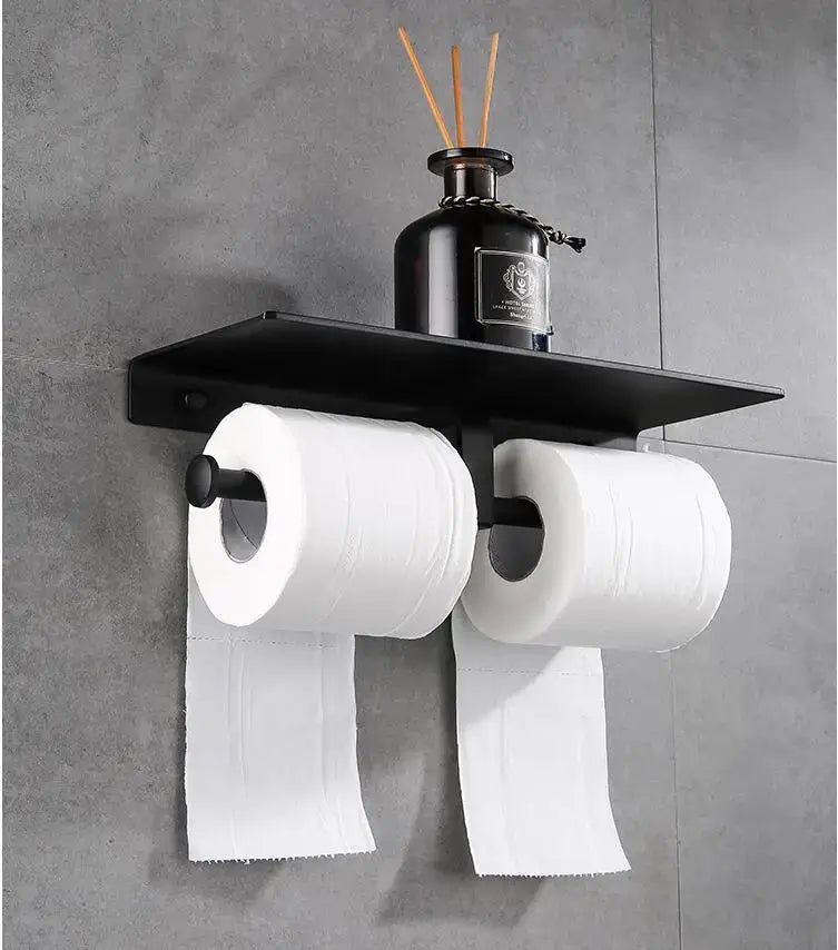 Modern black aluminum toilet paper holder with double rolls and shelf holding a dark diffuser bottle for bathroom use