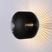 Modern black aluminum wall sconce with sleek layered fins casting warm sunburst patterns for elegant living room lighting