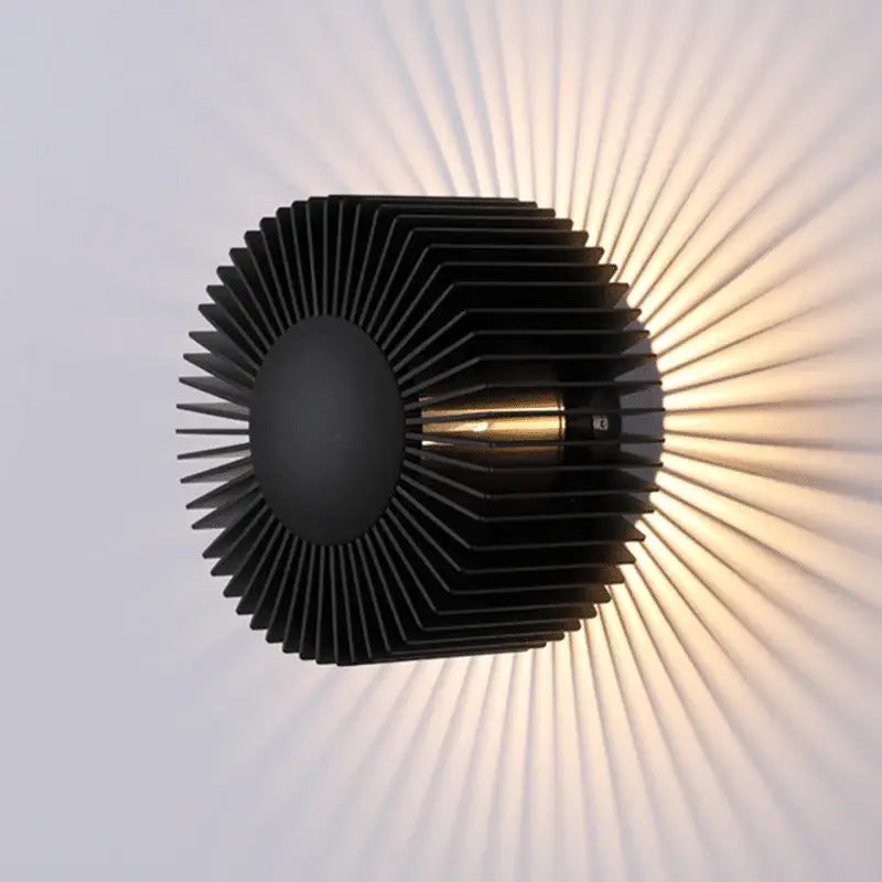 Modern black aluminum wall sconce with sleek layered fins casting warm sunburst patterns for elegant living room lighting