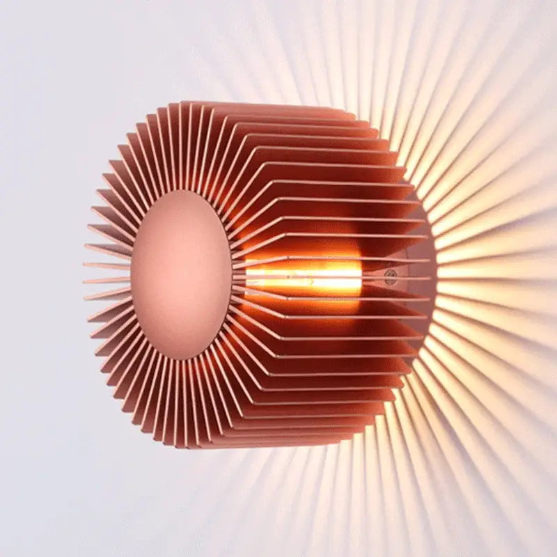 Modern black aluminum wall sconce with copper-colored radial design and warm filament bulb for elegant living room lighting