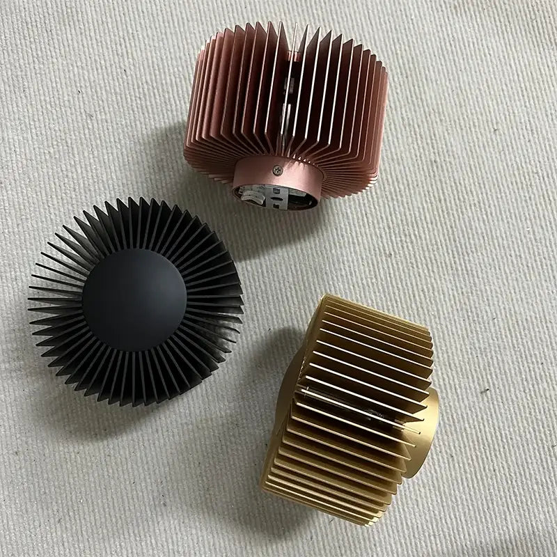Three heat sinks in rose gold black and brass finishes complement an elegant aluminum wall sconce for living room use