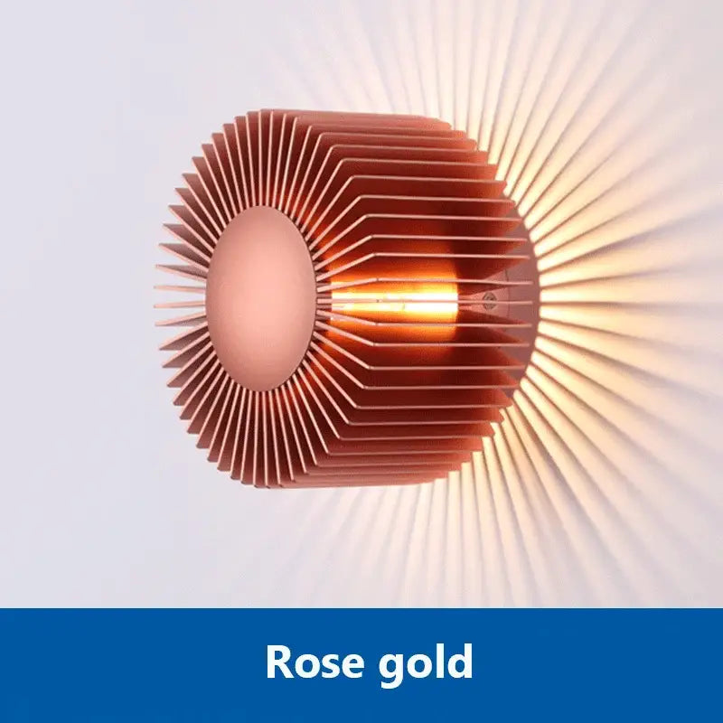 Modern black aluminum wall sconce with elegant rose gold sunburst design and sleek metallic fins for living room lighting