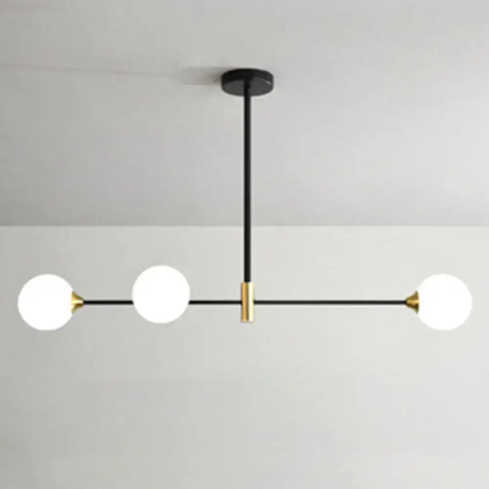 Modern black metal island pendant with brass accents and frosted glass globe bulbs featuring adjustable chain cord length