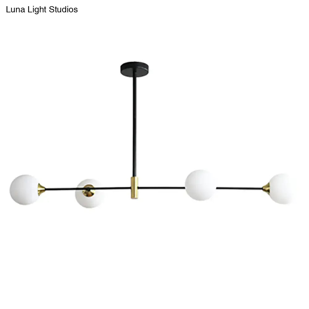 Modern black metal island pendant chandelier with brass accents and four frosted glass globes featuring adjustable chain cord length