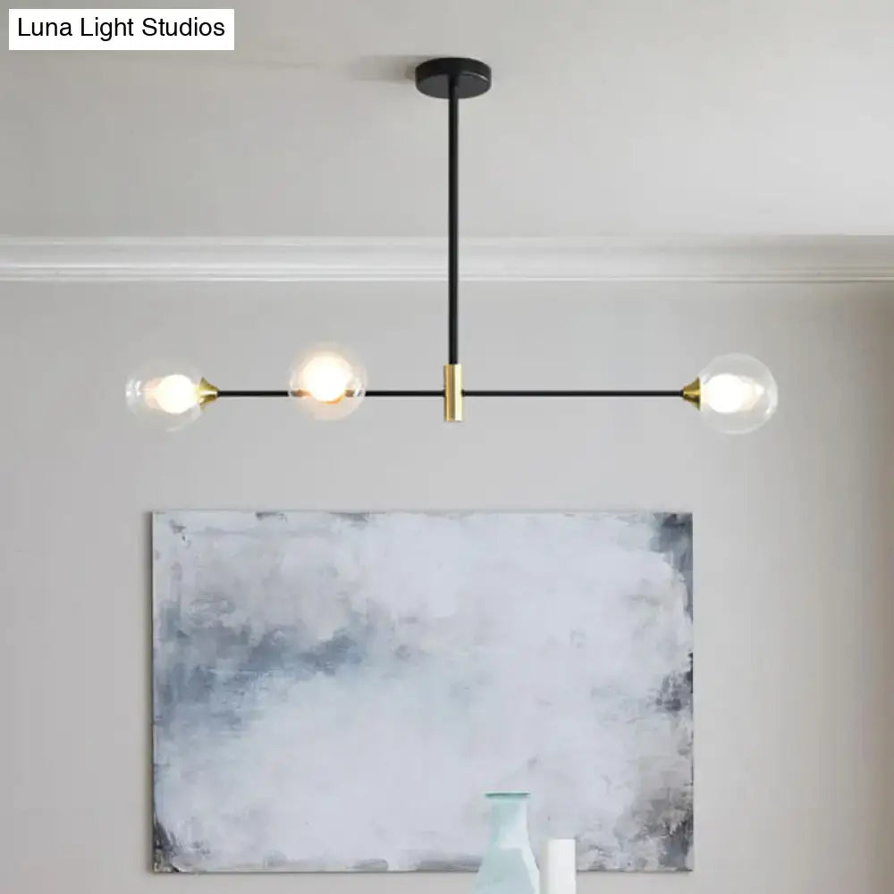 Modern black and brass metal island pendant with three clear glass globe bulbs and adjustable chain cord length for dining room chandelier