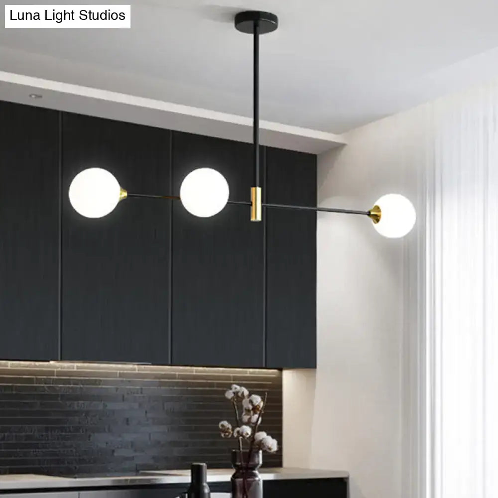 Modern black metal island pendant with brass accents and spherical white glass bulbs featuring adjustable chain cord length