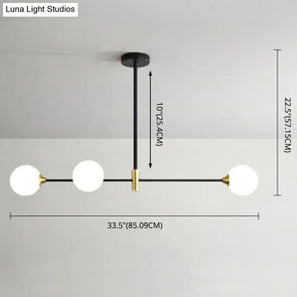 Modern black metal island pendant with brass accents and three frosted glass globes for dining room lighting adjustable chain cord length