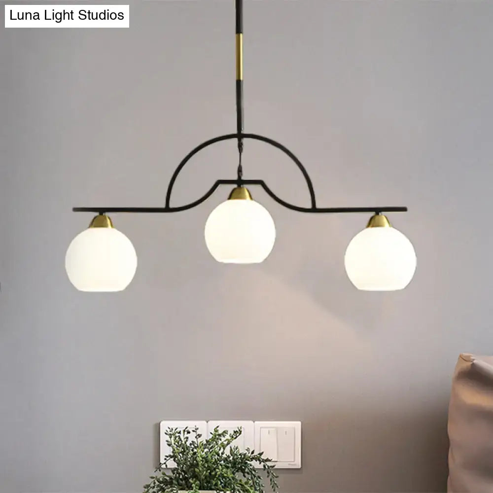 Decorbites modern island light fixture with black finish metal frame and cream clear glass globe shades with gold accents