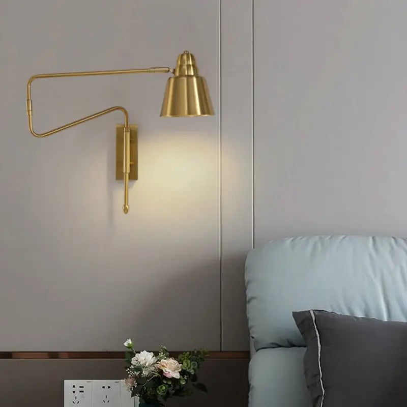 Brass-finished adjustable wall sconce with bell-shaped lampshade and retractable arm for modern bedroom lighting