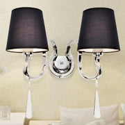 Modern black and chrome crystal wall mount light with double arms, fabric shades, and dangling teardrop accents