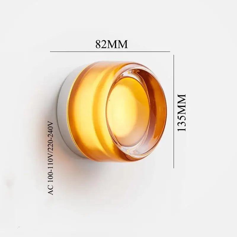 A translucent amber glass jar with white lid complements modern black and clear acrylic wall sconce light
