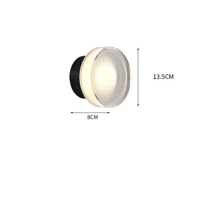 Modern black and clear acrylic wall sconce light with ribbed glass diffuser emitting warm white illumination