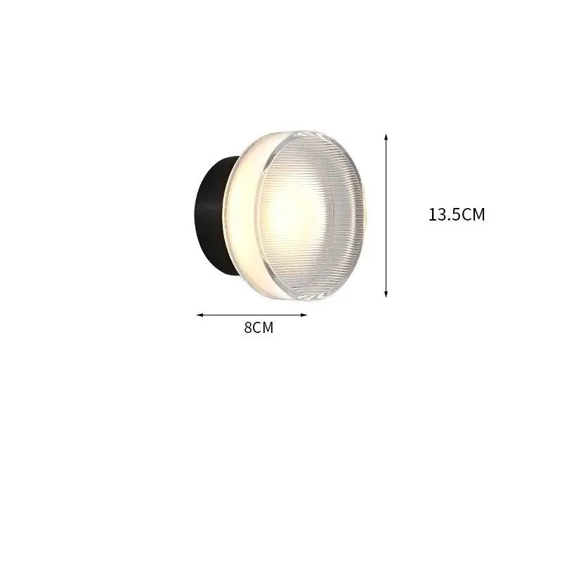 Modern black and clear acrylic wall sconce light with ribbed glass diffuser emitting warm white illumination
