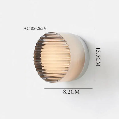 Modern black and clear acrylic wall sconce light with a ribbed amber glass shade and sleek white base for bedroom use