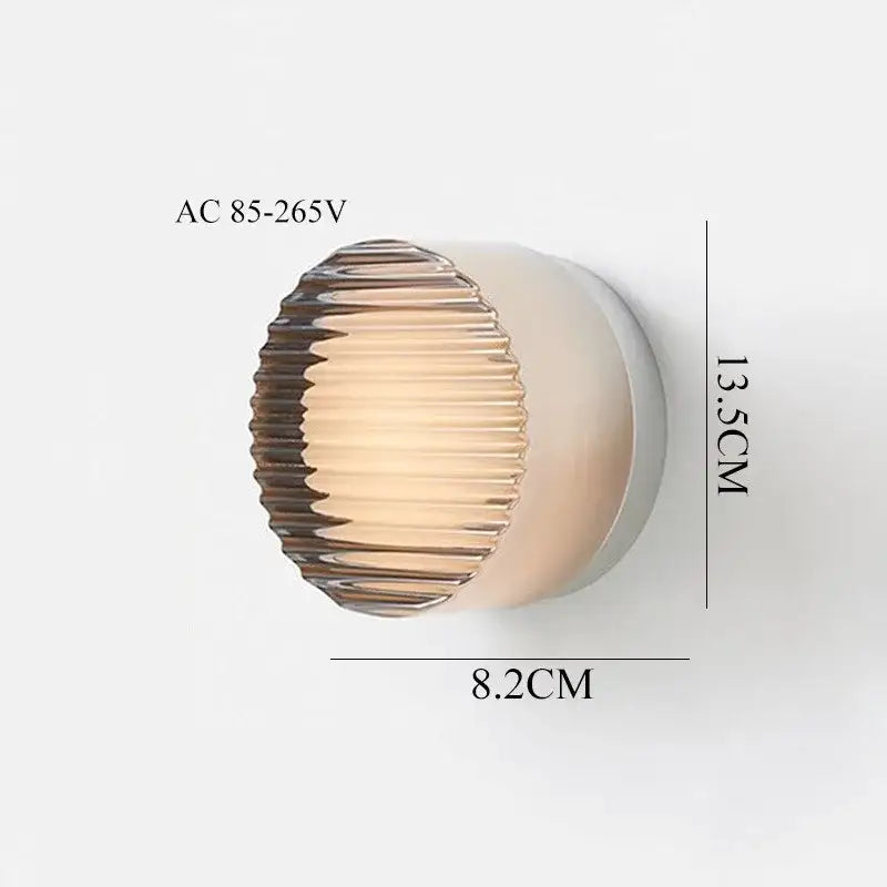 Modern black and clear acrylic wall sconce light with a ribbed amber glass shade and sleek white base for bedroom use