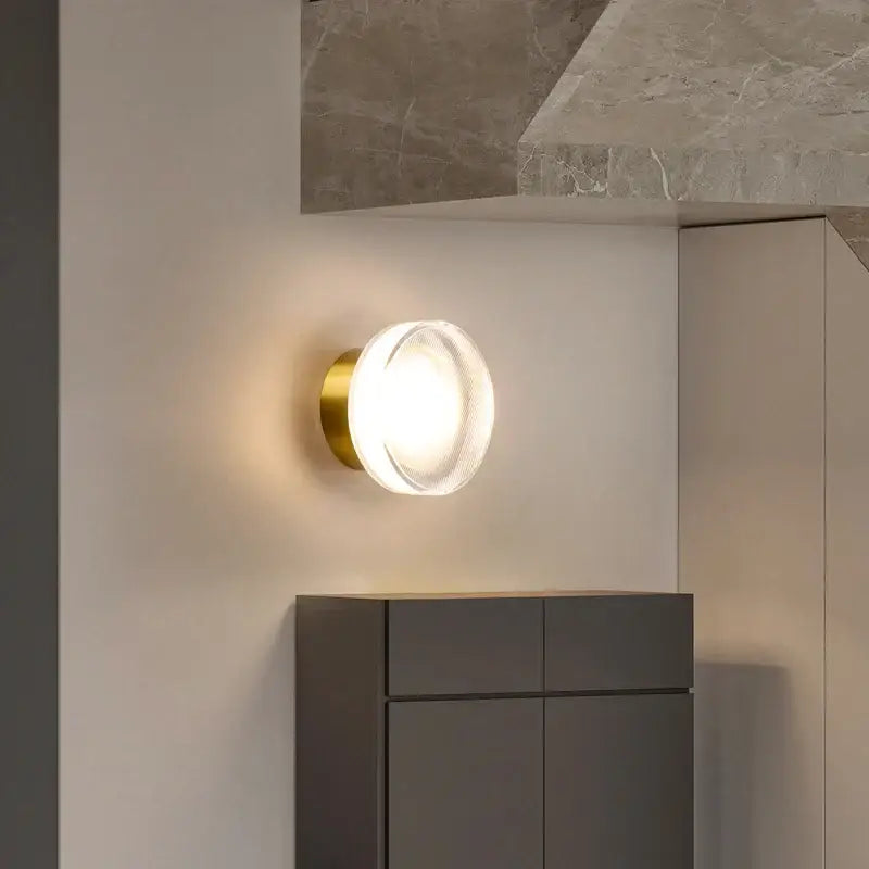 Modern black and clear acrylic wall sconce light with gold-finished metal base and clear glass diffuser for bedroom use