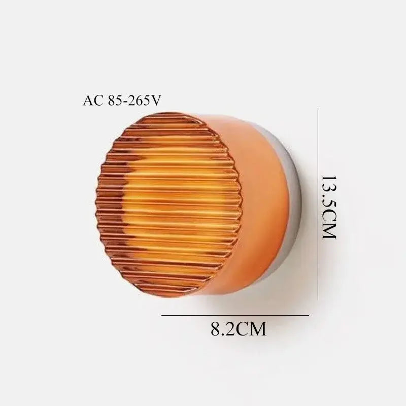 A sleek amber glass wall sconce light with ribbed texture and rounded edges for modern bedroom decor