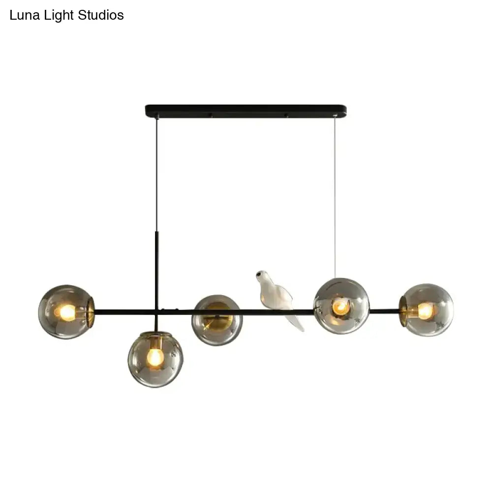 Modern black metal pendant light with five smoked glass shades and a white ceramic bird on central bar island pendant