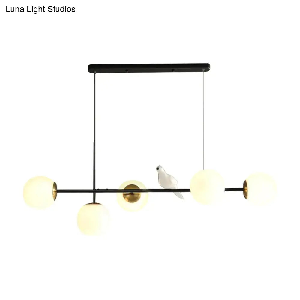 Black metal pendant light with five frosted glass shades and a white ceramic dove on the central bar island pendant